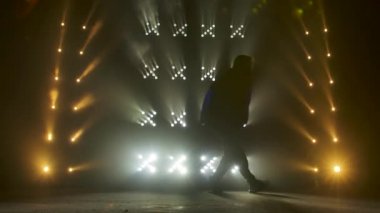 Yetenekli genç bir hip hop dansçısının silueti. Karanlık bir stüdyoda, dumanlı ve neon ışıklı bir sahnede hip hop sokak dansı. Dinamik ışıklandırma efektleri. Yaratıcı yetenekler. Yavaş çekim.
