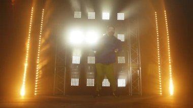 Yetenekli genç bir hip hop dansçısının silueti. Karanlık bir stüdyoda, dumanlı ve neon ışıklı bir sahnede hip hop sokak dansı. Dinamik ışıklandırma efektleri. Yaratıcı yetenekler. Yavaş çekim.