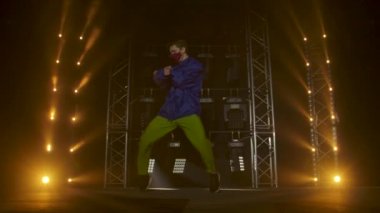 Yetenekli genç bir hip hop dansçısının silueti. Karanlık bir stüdyoda, dumanlı ve neon ışıklı bir sahnede hip hop sokak dansı. Dinamik ışıklandırma efektleri. Yaratıcı yetenekler. Yavaş çekim.