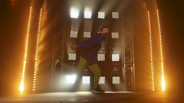 Silhouette of a talented young hip hop dancer. Hip hop street dance on a stage in dark studio with smoke and neon lighting. Dynamic lighting effects. Creative skills. Slow motion. — Stock Video