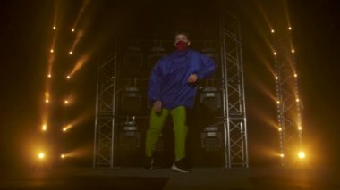 Yetenekli genç bir hip hop dansçısının silueti. Karanlık bir stüdyoda, dumanlı ve neon ışıklı bir sahnede hip hop sokak dansı. Dinamik ışıklandırma efektleri. Yaratıcı yetenekler. Yavaş çekim.