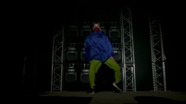 Yetenekli genç bir hip hop dansçısının silueti. Karanlık bir stüdyoda, dumanlı ve neon ışıklı bir sahnede hip hop sokak dansı. Dinamik ışıklandırma efektleri. Yaratıcı yetenekler. Yavaş çekim.
