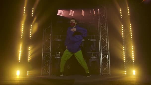 Silhouet van een getalenteerde jonge hiphopdanser. Hip hop straat dans op een podium in donkere studio met rook en neon verlichting. Dynamische lichteffecten. Creatieve vaardigheden. Langzame beweging. — Stockvideo