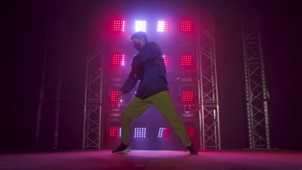 Silhouet van een getalenteerde jonge hiphopdanser. Hip hop straat dans op een podium in donkere studio met rook en neon verlichting. Dynamische lichteffecten. Creatieve vaardigheden. Langzame beweging. — Stockvideo
