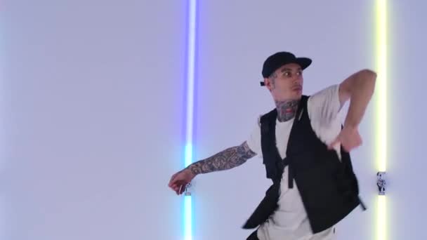 Profesionální hip hop tanečník praktikující street dance prvky proti jasným neonovým světlům ve studiu. Stylový muž tančí energicky ve zpomaleném filmu. Zavřít. — Stock video