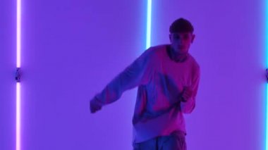 Havalı, genç, yetenekli hip hop 'çı çocuk, parlak neon ışıkların arka planında dans ediyor, inanılmaz jestler ve hareketler yapıyor. Sokak dansı. Kapatın. Yavaş çekim.