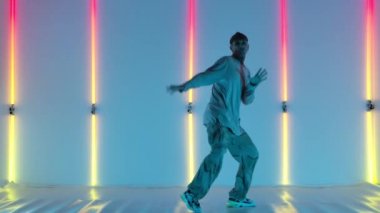 Havalı, genç, yetenekli hip hop 'çı çocuk, parlak neon ışıkların arka planında dans ediyor, inanılmaz jestler ve hareketler yapıyor. Sokak dansı. Yavaş çekim.