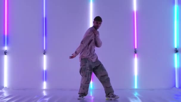 Cool ung talangfull hip hop kille dansar mot bakgrund av ljusa neonljus, utför fantastiska gester och rörelser. Gatudans. Långsamma rörelser. — Stockvideo