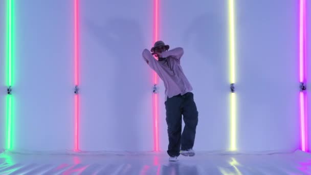 Homme dansant jeune danseur de rue talentueux effectuant des mouvements hip hop freestyle contre les lumières lumineuses au néon. Danseuse de rue bénéficiant d'une expression de danse moderne. Mouvement lent. — Video