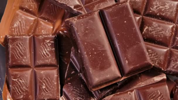 Čokoláda, kousky sladké čokolády otočené, zblízka. Gurmánská moučníková přísada. Cukrovinky, cukrovinky. Strukturované pozadí s lahodnými sladkostmi. Zpomalený pohyb. — Stock video