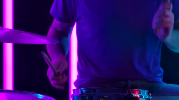 Musiker trommelt im Hintergrund rosa Neonröhren. Großaufnahme einer Männerhand, die auf Snare und Hihat mit Trommelstöcken spielt. Zeitlupe. — Stockvideo