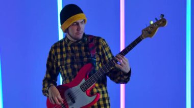 Müzisyen, stüdyodaki çok renkli neon boruların arka planına karşı beyaz kırmızı bir elektro gitarda solo çalıyor. Parti, müzik festivali, konser. Ağır çekim. Kapat..