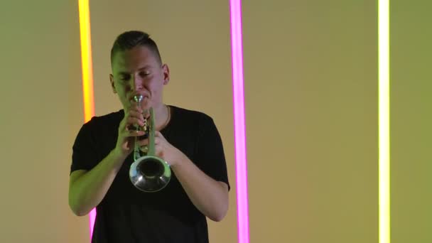 Músico trompetista tocando la trompeta en el estudio sobre el fondo de brillantes lámparas de neón multicolores. La expresión del talento. En cámara lenta. De cerca.. — Vídeos de Stock