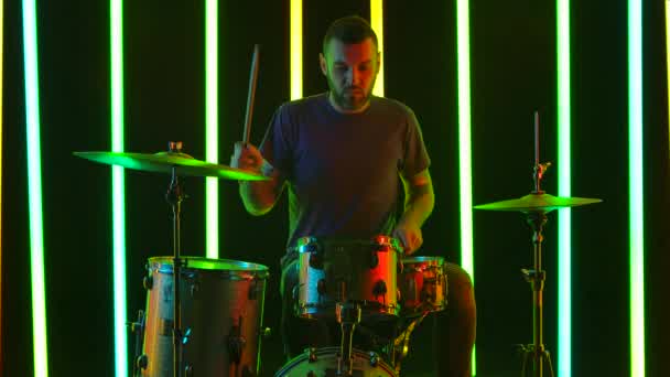 The talented drummer performs a drum solo in the studio against a background of bright neon lights. Rock musician playing rock music at a concert. Slow motion. Close up. — Stock Video