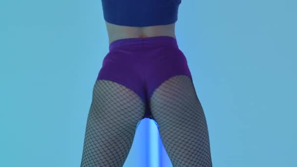 Young woman sexually moves her ass, dances twerk in slow motion. Prey shaking. Hot female dancing twerk erotically in studio against backdrop of bright neon lights. Close up. — Vídeo de stock