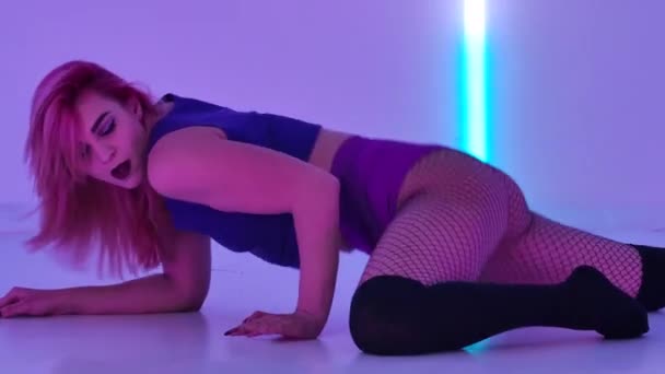 Side view attractive sexy woman in knee socks and shorts dancing twerk, shaking her ass. Sensual dancer twerks her buttocks in studio against backdrop of bright neon lights. Slow motion. Close up. — Stock video
