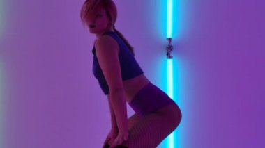 Pembe saçlı kadın ultraviyole neon ışıklarıyla dans ediyor. Ganimet dansı. Seksi popolar. Baştan çıkarma. Gece hayatı. Ağır çekim. Kapat..