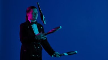 Gösteriş budalası karanlık bir stüdyoda lobutları çeviriyor. Adam ustaca fırlatıyor ve onlara konsantre olan iğneleri yakalıyor. Mavi ekran, kroma anahtarı. Kapatın. Yavaş çekim.