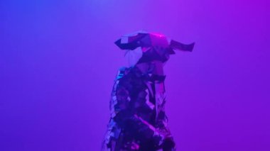 Neon mavisi pembe stüdyo arka planında dans eden aynalardan yapılmış kostümlü parlak gümüş boğa. 2021 'in sembolü, boğa, parlıyor ve siber disko partisinde kulüp ışıklarına yansıyor. Kapatın. Yavaş çekim.