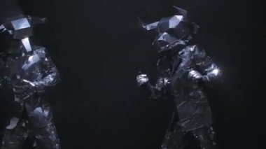 Parlak aynalı kostümlü, boğa kafalı ve boynuzlu iki aktör disko partisinde eğlenceli dans ediyor. Işıklara yansıyan siyah arka plandaki dumanlı stüdyoda yansıyan insanları göster. Kapatın. Yavaş çekim.