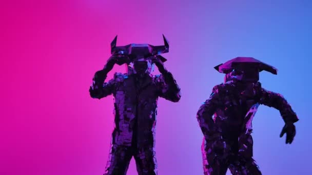 Dois atores em trajes espelhados brilhantes com uma cabeça de touros e chifres dançam em uma festa festiva. Mostre as pessoas espelhadas no fundo de luzes coloridas de néon rosa azul em um estúdio escuro. Fechar. — Vídeo de Stock