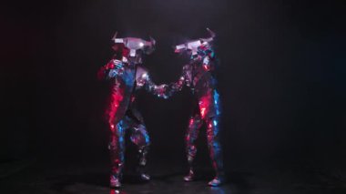 Aynalardan gelen parlak boğa kostümlü aktörler onları buraya davet ediyor. Yansıtıcı takım elbiseli boğalar siyah bir stüdyonun arka planına karşı renkli ışık demetlerinde parıldarlar. Yavaş çekim.