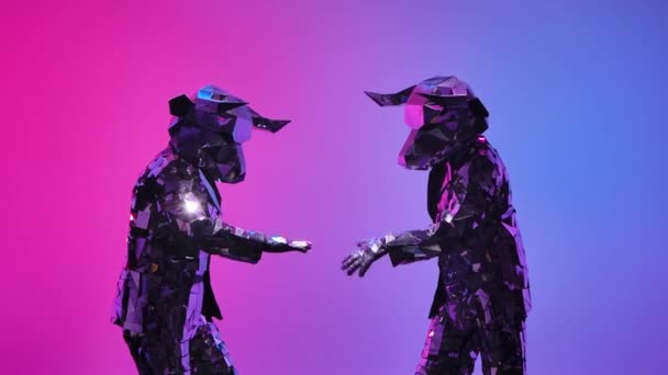 Pessoas cibernéticas espelhadas em trajes de touros com chifres se divertindo jogando as mãos no fundo do estúdio rosa azul neon. Símbolo de 2021, touro, brilha e reflete-se na luz de clube. Fecha. Movimento lento. — Vídeo de Stock