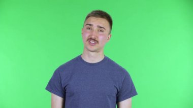 Öfkeyle kameraya bakan genç bir adamın portresi ellerini sallıyor, omuzlarını silkiyor, bu nasıl oluyor? Stüdyoda yeşil ekranda poz veren bıyıklı yakışıklı bir erkek. Kapat..