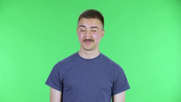 Portrait of a young man refusing stress and taking situation, calming down, breathing deeply. Cute male with a mustache in a blue t-shirt posing on a green screen in the studio. Close up. — Stock Video