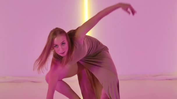 一个灵活的年轻女舞蹈家表演的性感的蔑视现代舞。性感的艺术家喜欢在有明亮霓虹灯的黑暗工作室里跳舞和徘徊。靠近点慢动作. — 图库视频影像