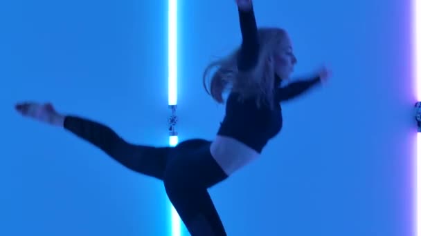 Uroczy tancerz w czarnym trykocie wykonujący akrobatyczne elementy tańca kontemplacyjnego na tle jasnych neonów. Elastyczna seksowna kobieta porusza się w zwolnionym tempie. Zamknij się.. — Wideo stockowe