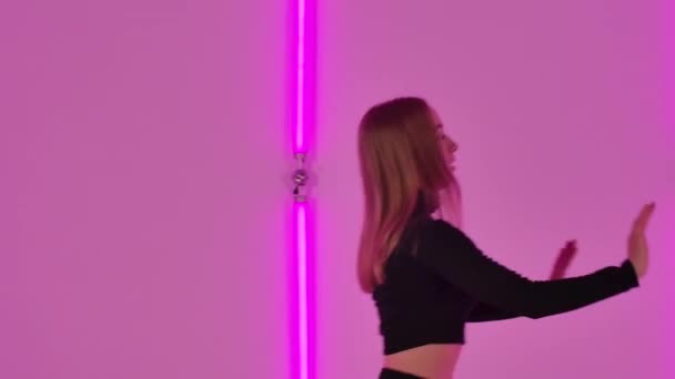 Sensuellt modernt förakt med aerobiska element utförda av smal dansare mot bakgrund av starkt neonljus. Feminin kvinnlig praktik modern koreografi i mörk studio. Närbild. Långsamma rörelser. — Stockvideo