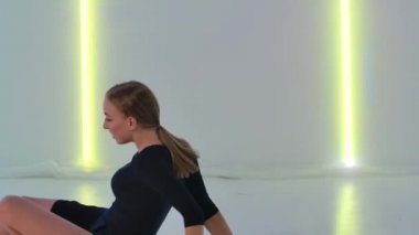 Zayıf dansçı tarafından icra edilen akrobatik öğelere nazik bir aşağılama. Modern koreografiden hoşlanan genç ve güzel bir kadın karanlık stüdyoda parlak neon ışıkların önünde. Kapatın. Yavaş çekim.