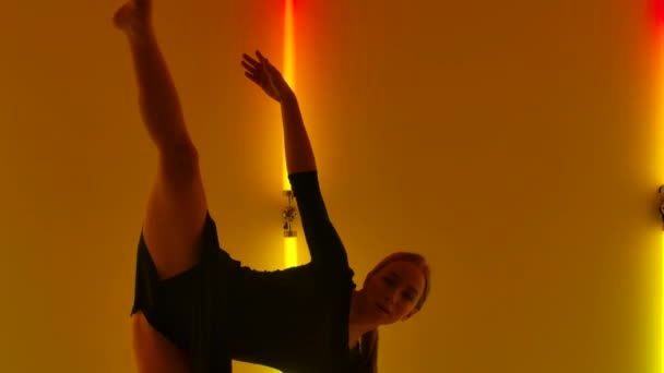 Aantrekkelijke danser voert emotioneel een moderne choreografie van minachting uit tegen de achtergrond van rood-gele neonlichten. Jonge vrouw danst contemp met elementen van acrobatiek. Sluit maar af. Langzame beweging. — Stockvideo