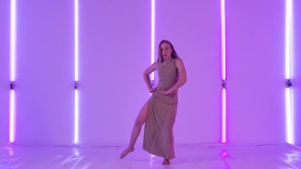 女性舞蹈演员在明亮的霓虹灯背景下表现出性感的蔑视和优雅的跳跃。年轻女子在一间黑暗的演播室里跳现代舞.慢动作. — 图库视频影像