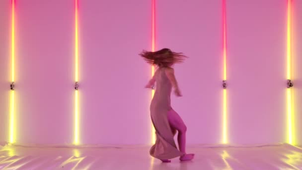 Genç ve esnek bir bayan dansçı tarafından yapılan seksi modern küçümseme dansı. Şehvetli sanatçılar dans etmekten ve parlak neon ışıkları olan karanlık bir stüdyoda dolaşmaktan hoşlanırlar. Yavaş çekim. — Stok video