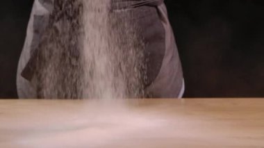 Kadın aşçı mutfaktaki masada doğal buğday unu süzüyor. Beyaz toz yavaş çekimde düşer ve bir tümsek oluşturur. Hamur hazırlama süreci. Kapat..