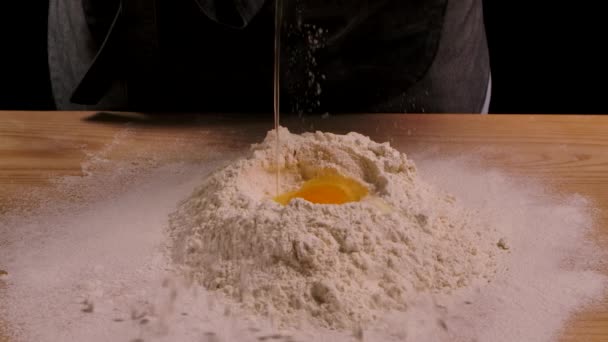 Un yığınına düşen yumurtanın yavaş hareketi. Un içine yumurta düşüyor. Yemek blogu, un ve fırın ürünleri. Ev yapımı hamur pişirme işlemi. Pişirme ve şekerleme pişirme adımları. Kapat.. — Stok video