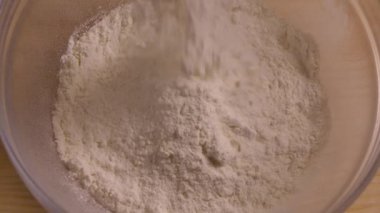 Cam bir kaseye düşen beyaz buğday unu manzarası. Hamur yapmak için un ekiyorum. Yemek blogu, un ve fırın ürünleri. Ev yapımı hamur pişirme işlemi. Kapatın. Yavaş çekim.