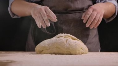 Kadın elleri masada un içinde hamur yoğuruyor. Undan el yapımı hamur yapma süreci. Ekmek yapmak, yemek pişirmek ve şekerleme yapmak. Yaklaşın, ağır çekim..