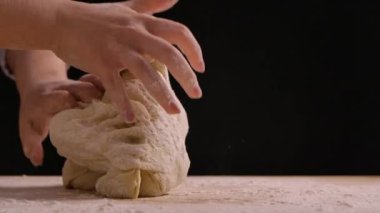 Kadın elleri masada un içinde hamur yoğuruyor. Undan el yapımı hamur yapma süreci. Ekmek yapmak, yemek pişirmek ve şekerleme yapmak. Yaklaşın, ağır çekim..