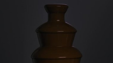 Çikolata çeşmesi. Sıvı çikolata bir çağlayandan açık mor arka plana doğru akar. Açık ve koyu renkli sıcak çikolata tatlısı. Tatlı yemek. Kutlama dekorasyonu. Kapatın. Yavaş çekim.