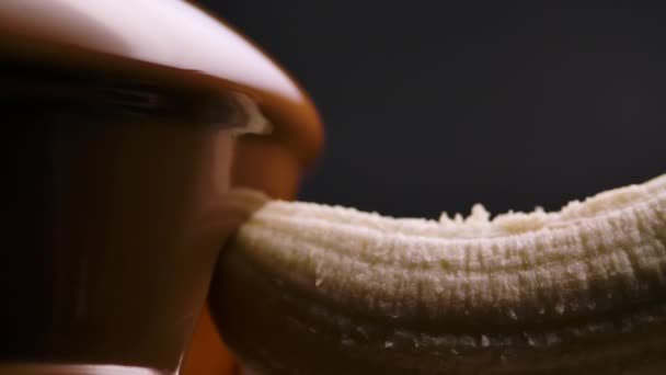 El chocolate con leche derretida fluye en una fuente de chocolate. El plátano maduro se sumerge y se envuelve en chocolate líquido caliente que desciende de las cascadas. Fondue. Fiesta y celebración. De cerca. Movimiento lento. — Vídeo de stock