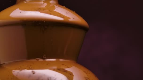 Fonte de chocolate. O cacau é derramado sobre a sobremesa líquida derretida e se dissolve no líquido. Doce gostoso em um fundo roxo. Decoração festiva. Fecha. Movimento lento. — Vídeo de Stock