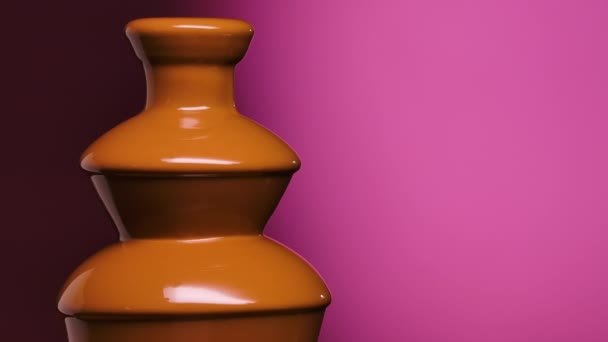 Flux de chocolat liquide. Fontaine cascades de chocolat au lait fondu chaud sur un fond violet. Gros plan de chocolat chaud liquide coulant au ralenti. — Video