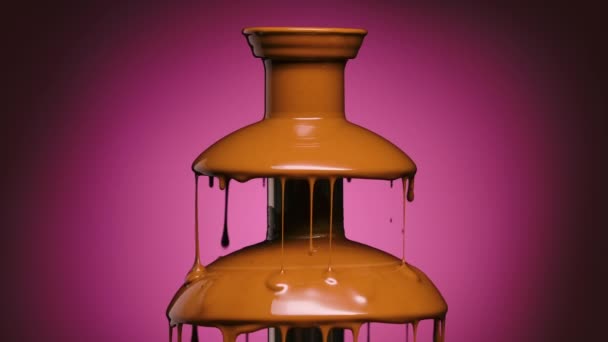 Stop chocolade fontein op een paarse achtergrond. Warme gesmolten melkchocolade druipt uit de cascade. Druppels zoete chocolade dessert. Einde van het feest. Sluit maar af. Langzame beweging. — Stockvideo