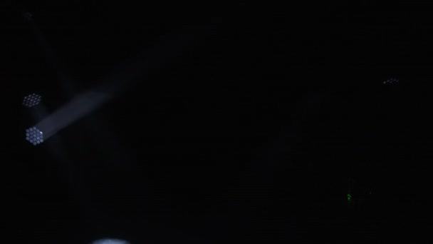Strobe feixes brancos dinâmicos de luz de palco no fundo escuro fumegante do estúdio. Mostra de hologramas. Equipamentos de iluminação e efeitos de luz para design, sala de concertos e iluminação de palco durante o show ou discoteca. — Vídeo de Stock