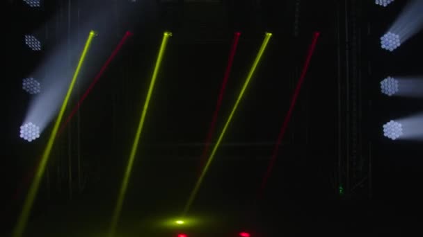 Красочные огни сцены. Белые прожекторы и желтые красные лазерные голограммы вращаются, вращаются и излучают яркие лучи света. Осветительное оборудование и световые эффекты для шоу или дискотеки. — стоковое видео