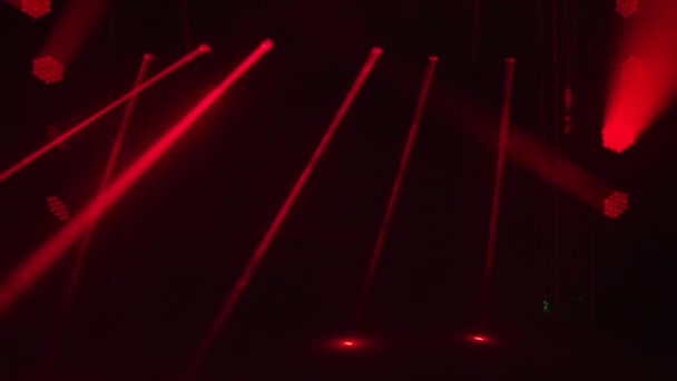 Ярко-красные лазерные лампы и прожекторы динамически вращаются и перемещаются по темной сцене. Сияющая пустая сцена для праздничного шоу, церемонии награждения или рекламы. Ночное лазерное шоу голограмм. — стоковое видео