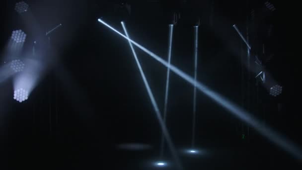 动态的白光束激光全息图和聚光灯照亮了一个空旷的黑暗舞台。探照灯旋转和眨眼。假日节目、颁奖典礼或广告的照明设备及效果. — 图库视频影像